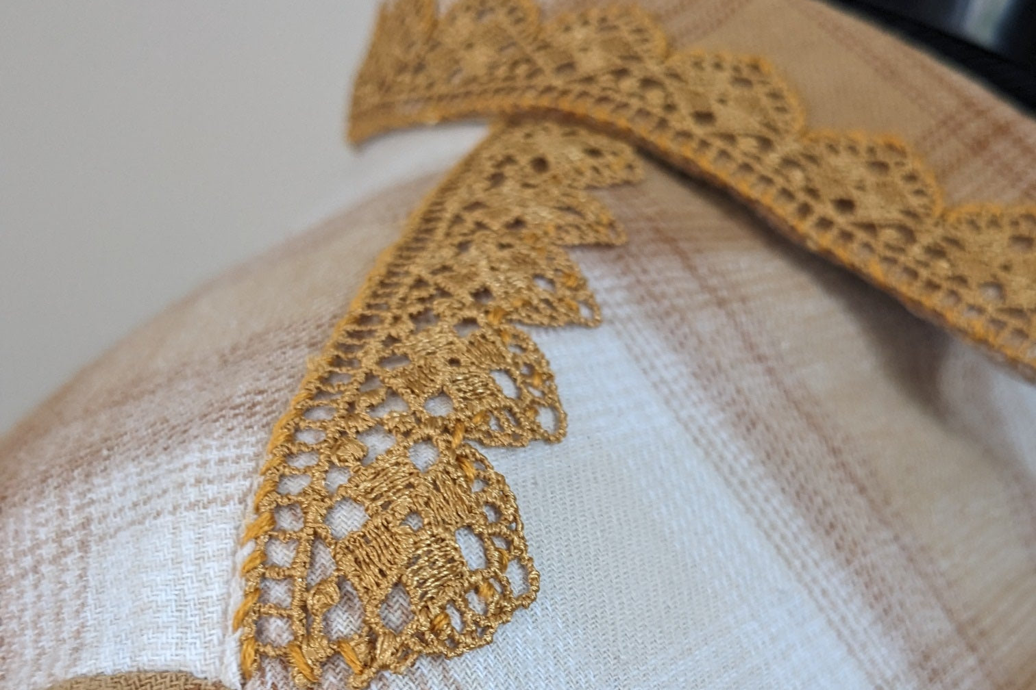 Close-up of a garment with a yellow lace collar on a neutral background